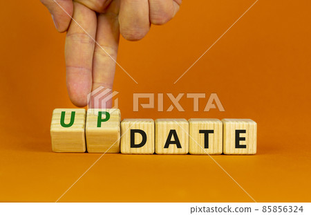 Date or update symbol. Businessman turns wooden cubes and changes the concept word date to update. Beautiful orange table, orange background, copy space. Business and date or update concept. 85856324