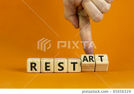 Rest and restart symbol. Businessman turns wooden cubes and changes the word 'rest' to 'restart'. Beautiful orange background, copy space. Business, rest and restart concept. Rest and restart symbol. Businessman turns wooden cubes and changes the word 'rest' to 'restart'. Beautiful orange background, copy space. Business, rest and restart concept. 85856329