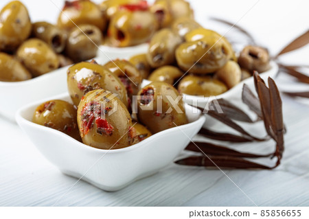 Spiced green olives in oil on a wooden table. Spiced green olives in oil on a wooden table. 85856655