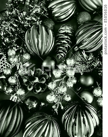 Christmas background with Christmas decorations, holiday balls, bells, bows, fir cone, Christmas tinsel. Happy New Year and Merry Christmas. Black and white monochrome photo with green filter. 85856816