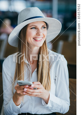 Airport business woman on smart phone at gate waiting in terminal. Air travel concept with young casual businesswoman sitting with hand luggage suitcase. Beautiful young mixed race female professional Airport business woman on smart phone at gate waiting in terminal. Air travel concept with young casual businesswoman sitting with hand luggage suitcase. Beautiful young mixed race female professional 85857032
