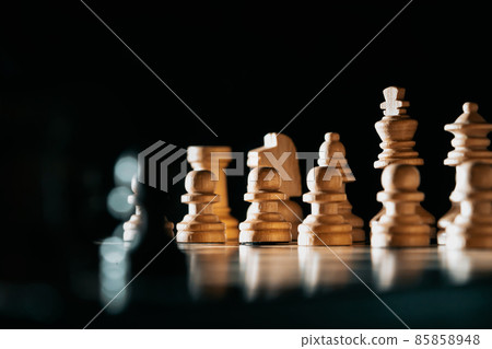 Pieces on chessboard. Board intelligence game - wooden chess on dark background. Business solutions Pieces on chessboard. Board intelligence game - wooden chess on dark background. Business solutions 85858948
