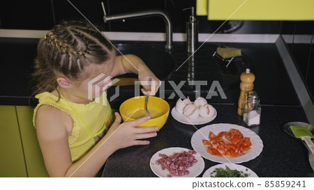 Smart girl learning to cook. Young mistress children to cook a Neapolitan egg fried omelette from salame affumicato sausage. 85859241