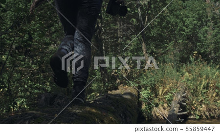 Traveler photographing scenic view in forest river. Wood bridge fallen tree. One caucasian woman shooting nice magic look. Girl take photo on camera. Traveler photographing scenic view in forest river. Wood bridge fallen tree. One caucasian woman shooting nice magic look. Girl take photo on camera. 85859447