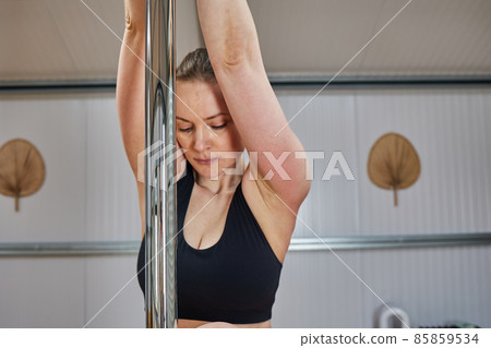closed portrait of European woman on pole bar prepared to perform suspension exercises with sportswear 85859534