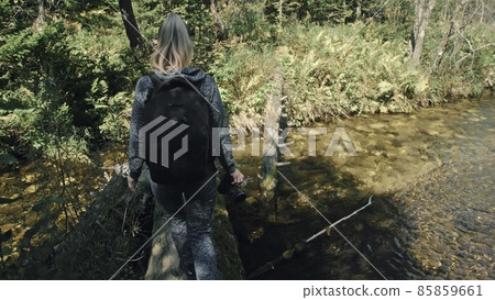 Traveler photographing scenic view in forest river. Wood bridge fallen tree. One caucasian woman shooting nice magic look. Girl take photo on camera. Traveler photographing scenic view in forest river. Wood bridge fallen tree. One caucasian woman shooting nice magic look. Girl take photo on camera. 85859661
