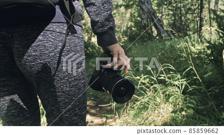 Traveler photographing scenic view in forest. One caucasian woman shooting close up look. Girl hold dslr mirrorless camera in his hand. Outdoor. Traveler photographing scenic view in forest. One caucasian woman shooting close up look. Girl hold dslr mirrorless camera in his hand. Outdoor. 85859662