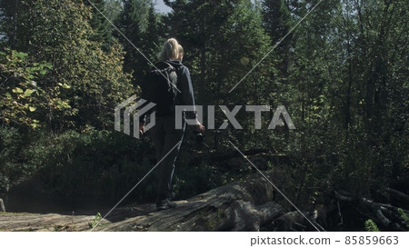 Traveler photographing scenic view in forest river. Wood bridge fallen tree. One caucasian woman shooting nice magic look. Girl take photo on camera. Traveler photographing scenic view in forest river. Wood bridge fallen tree. One caucasian woman shooting nice magic look. Girl take photo on camera. 85859663