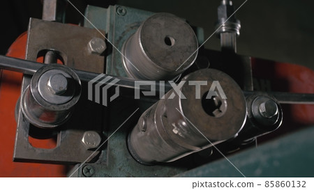 Forge workshop on table. Worker bends the metal rod on the wrought iron round bending machine. Manufacturing of a designer part from a metal rod. Forge workshop on table. Worker bends the metal rod on the wrought iron round bending machine. Manufacturing of a designer part from a metal rod. 85860132