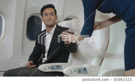 Air hostess in uniform service take care of male passengers checking seats boarding pass 85862323