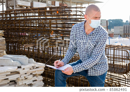 Worker in mask with checklist collecting order at hardware store 85862491