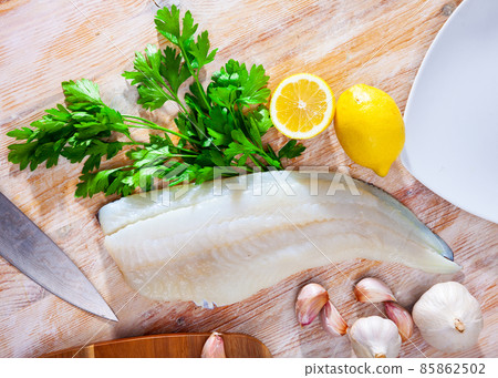 Raw codfish fillet on wooden table with condiments 85862502