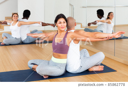 Athletic korean woman performing paired yoga exercises with male partner Athletic korean woman performing paired yoga exercises with male partner 85862778