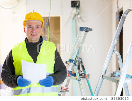 Repair man standing in apartment with documentation Repair man standing in apartment with documentation 85863015