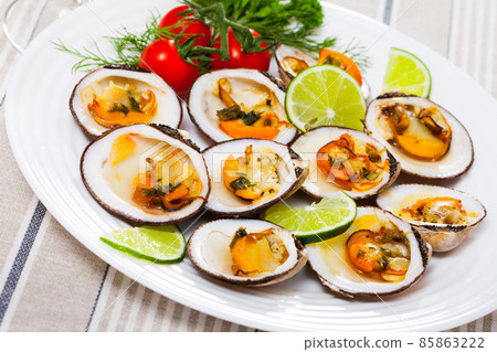 Baked in oven with sauce dog cockle with lemon and fresh greens 85863222