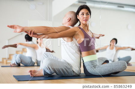 Athletic korean woman performing paired yoga exercises with male partner 85863249