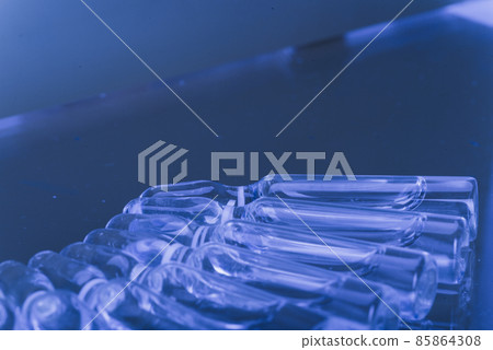 Glass medical ampoule vial for injection. Medicine is liquid sodium chloride with of aqueous solution in ampulla. Close up. Bottles ampule multicolor. 85864308