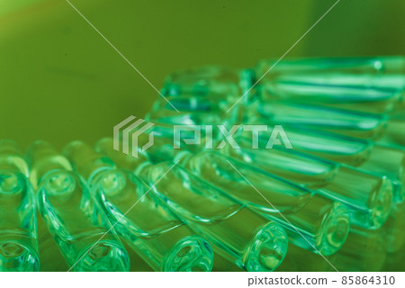 Glass medical ampoule vial for injection. Medicine is liquid sodium chloride with of aqueous solution in ampulla. Close up. Bottles ampule multicolor. 85864310