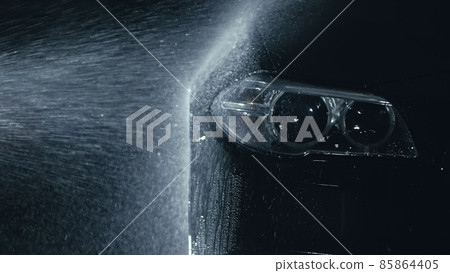 Car headlight wash. Washing modern vehicle body by high pressure jet wash hose water. Auto glass headlamp, angel eyes in drops. 85864405