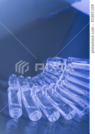 Glass medical ampoule vial for injection. Medicine is liquid sodium chloride with of aqueous solution in ampulla. Close up. Bottles ampule multicolor. 85865109