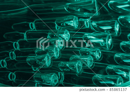Glass medical ampoule vial for injection. Medicine is liquid sodium chloride with of aqueous solution in ampulla. Close up. Bottles ampule multicolor. 85865137