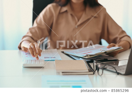 Cropped shot businesswoman holding financial document and using calculator. 85865296