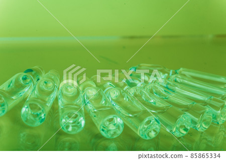 Glass medical ampoule vial for injection. Medicine is liquid sodium chloride with of aqueous solution in ampulla. Close up. Bottles ampule multicolor. Glass medical ampoule vial for injection. Medicine is liquid sodium chloride with of aqueous solution in ampulla. Close up. Bottles ampule multicolor. 85865334