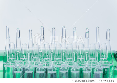 Glass medical ampoule vial for injection. Medicine is liquid sodium chloride with of aqueous solution in ampulla. Close up. Bottles ampule multicolor. 85865335