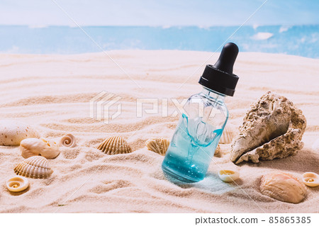 Glass bottle with serum gel cosmetic product with air bubbles on the background of seashells and sea beach sand. product presentation on a sandy background Glass bottle with serum gel cosmetic product with air bubbles on the background of seashells and sea beach sand. product presentation on a sandy background 85865385