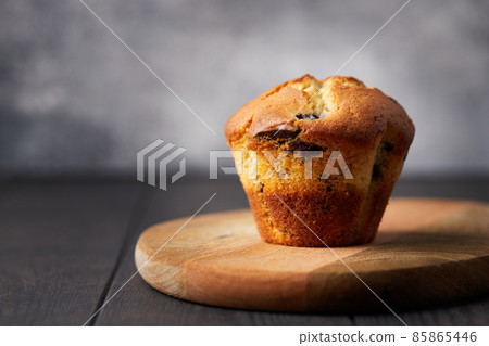 Muffin with chocolate and blueberries on a wooden stand on a dark background. Front view. Muffin with chocolate and blueberries on a wooden stand on a dark background. Front view. 85865446