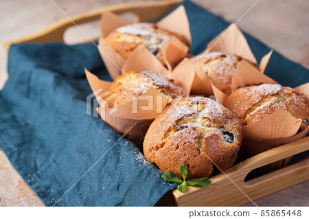 A group of muffins with berries and chocolate on a tray. Front view. 85865448