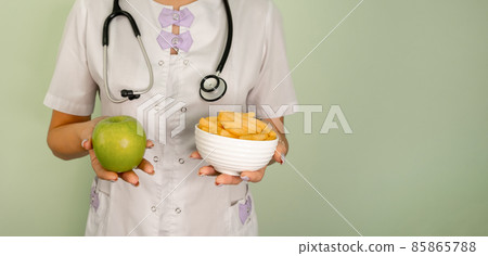 Young woman makes a choice between crisps and apple. 85865788