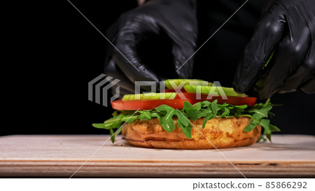 Craft burger is cooking on black background. Consist: sauce, arugula, tomato, red onion rings fries, cucumber, cheese, air bun and marble meat beef. 85866292