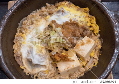 Close up of Mixed Toji the traditional Japanese food. The ingredients is cooked by Crispy pork cutlets, deep-fried prawns and tender eels delicately topped with soft eggs. 85866894