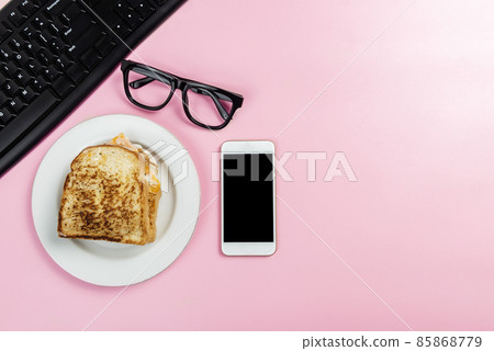 Laptop with mobile phone and bread toast on the plate 85868779