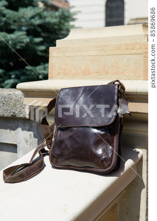 Outdoor photo of a brown leather Messenger bag. 85869686