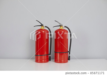 Two red standard fire extinguishers inside the building. Chemical, carbon dioxide or air pressurized water fire extinguishers placed on a table. Fire safety and fire prevention concept 85871171