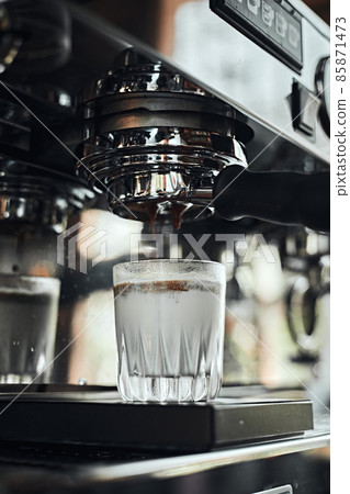 Close up of espresso pouring from coffee machine. Close up of espresso pouring from coffee machine. 85871473