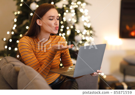 Woman blowing kiss during virtual date on laptop Woman blowing kiss during virtual date on laptop 85871559