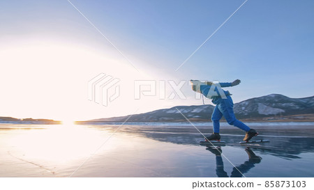The child train on ice professional speed skating. The girl skates in the winter in sportswear, sport glasses, suit. Outdoor slow motion. 85873103