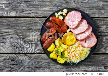 bratwurst, pork, potatoes, sauerkraut on a plate 85873800
