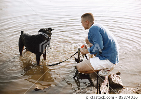 Man with rotweiller dog playing together in the lake 85874010