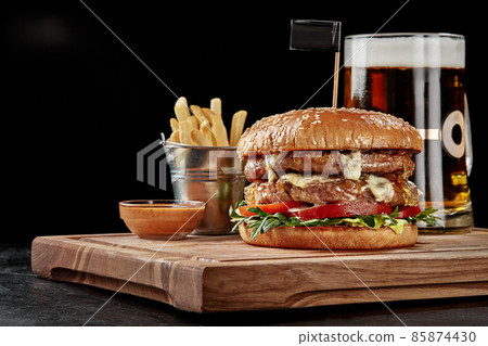 Burger with two patties, blue cheese, caramelized onions, tomatoes and arugula served with amber lager, fries and sauce 85874430