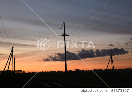 Horizon. Evening dawn, dark sky and a few electric pylons. 85875597