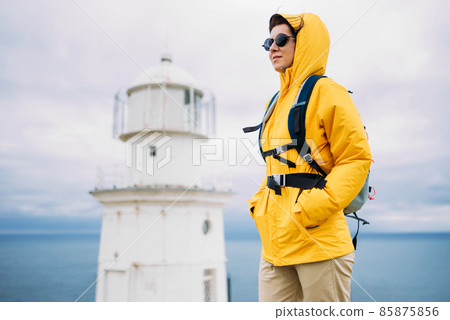 Portrait of a female traveler on the background of the sea. The concept of adventure, travel and hiking. A female tourist enjoys a beautiful landscape during a hike. Portrait of a tourist by the sea 85875856