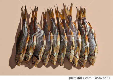 Lots of dried or jerky salty roach, palatable clipfish on pink background. Famous beer snack. Traditional way of preserving fish. Close up 85876385