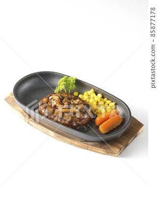 Japanese-style hamburger steak with parsley, carrot glass, corn, and mushroom sauce on an iron plate taken on a white background Japanese-style hamburger steak with parsley, carrot glass, corn, and mushroom sauce on an iron plate taken on a white background 85877178