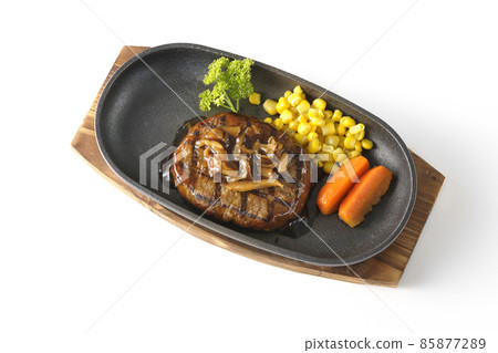 A bird's-eye view of a Japanese-style hamburger steak with parsley, carrot glass, corn, and mushroom sauce on an iron plate on a white background. 85877289