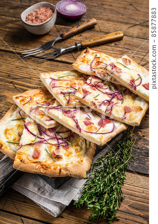 Flammkuchen or tarte flambee with cream cheese, bacon and onions. Wooden background. Top view 85877883