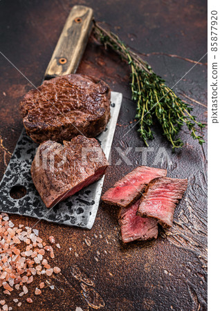 Rare Grilled fillet mignon beef steak on a meat cleaver. Dark background. Top view 85877920